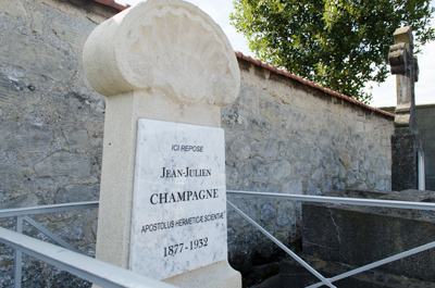 Photographie de la tombe restaurée de Julien Champagne, vue de trois-quart sur la stelle avec le fond du cimetière en arrière-plan
